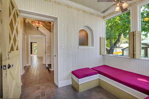 Hallway with wood walls, crown molding, and dark wood-style floors