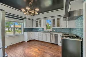 Kitchen featuring white cabinets, ventilation hood, dark wood finished floors, glass fronted cabinets, and plenty of natural light