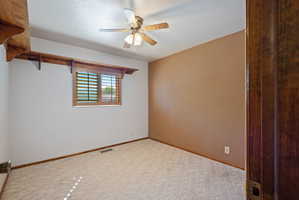 Carpeted empty room with a textured ceiling and ceiling fan