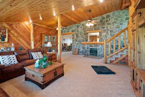 Carpeted living area with vaulted ceiling with beams, wood ceiling, a fireplace, and ceiling fan