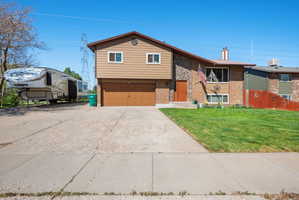 View of front facade featuring brick siding, an attached garage, concrete driveway, and a chimney