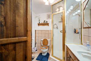Full bath with vanity, a shower stall, tile walls, and light tile patterned floors