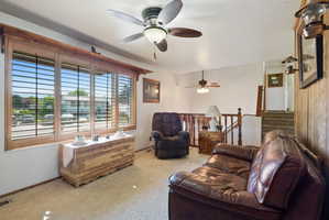 Living room with ceiling fan, carpet floors, and a textured ceiling
