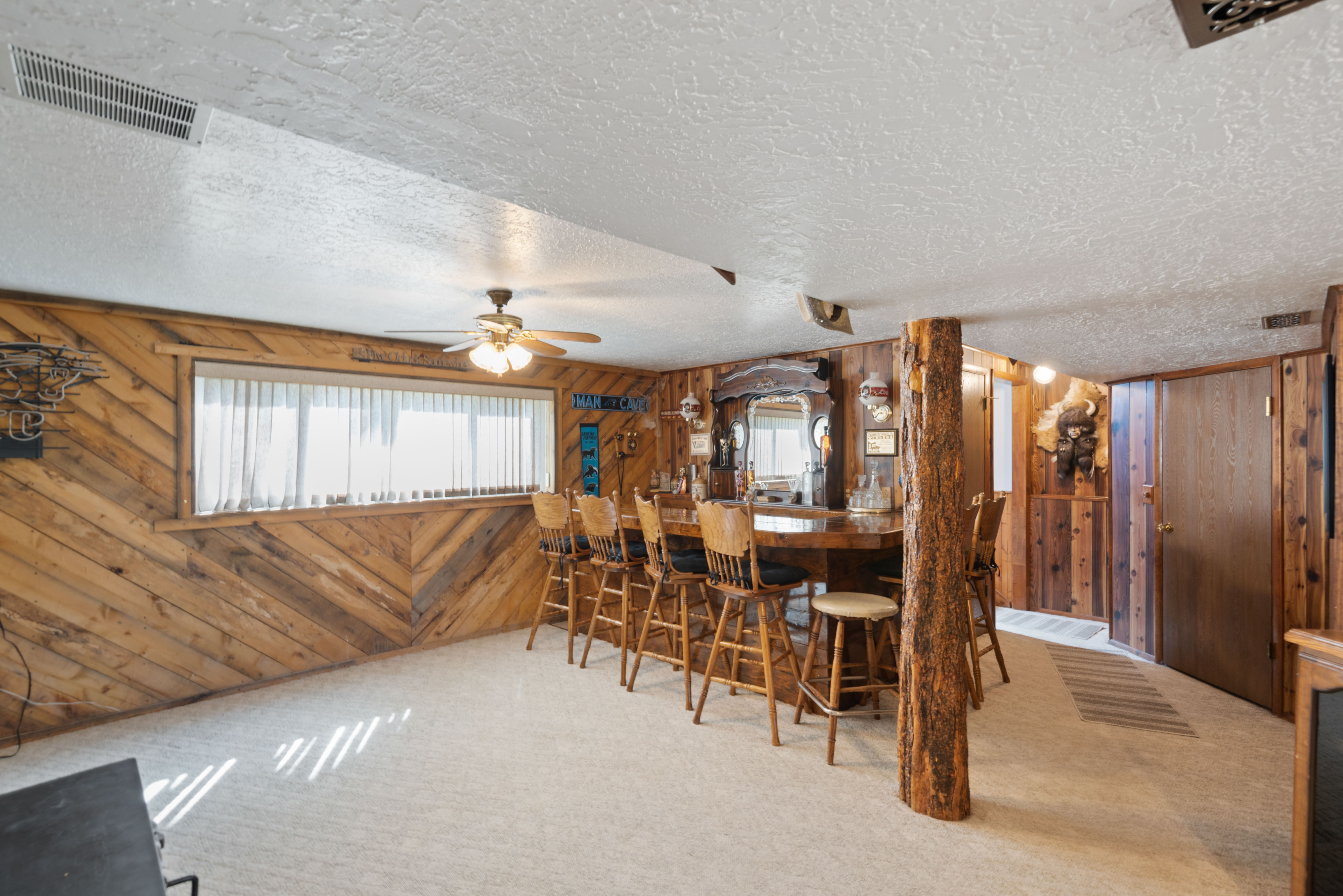 Carpeted dining area with wooden walls, ceiling fan, and a textured ceiling