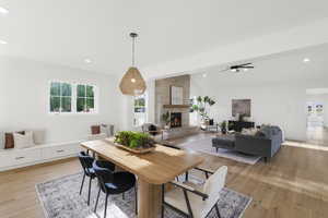 Dining room featuring lofted ceiling, light wood-type flooring, recessed lighting, a large fireplace, and a ceiling fan