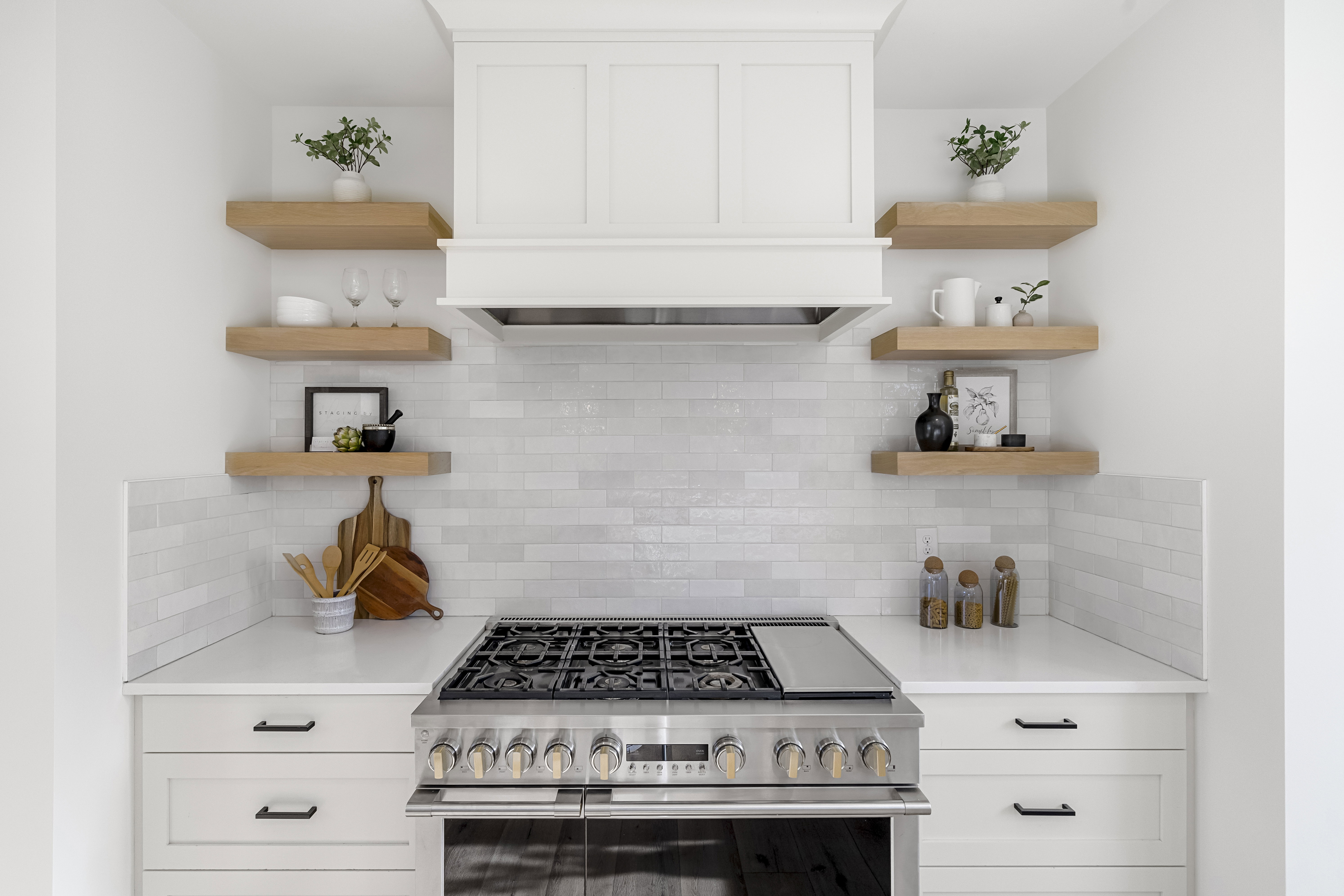Kitchen with white cabinetry, open shelves, high end stainless steel range oven, and decorative backsplash