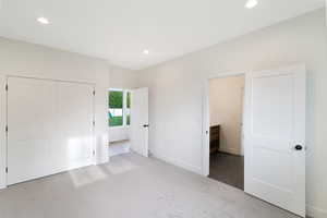 Unfurnished bedroom featuring light carpet, recessed lighting, and a closet