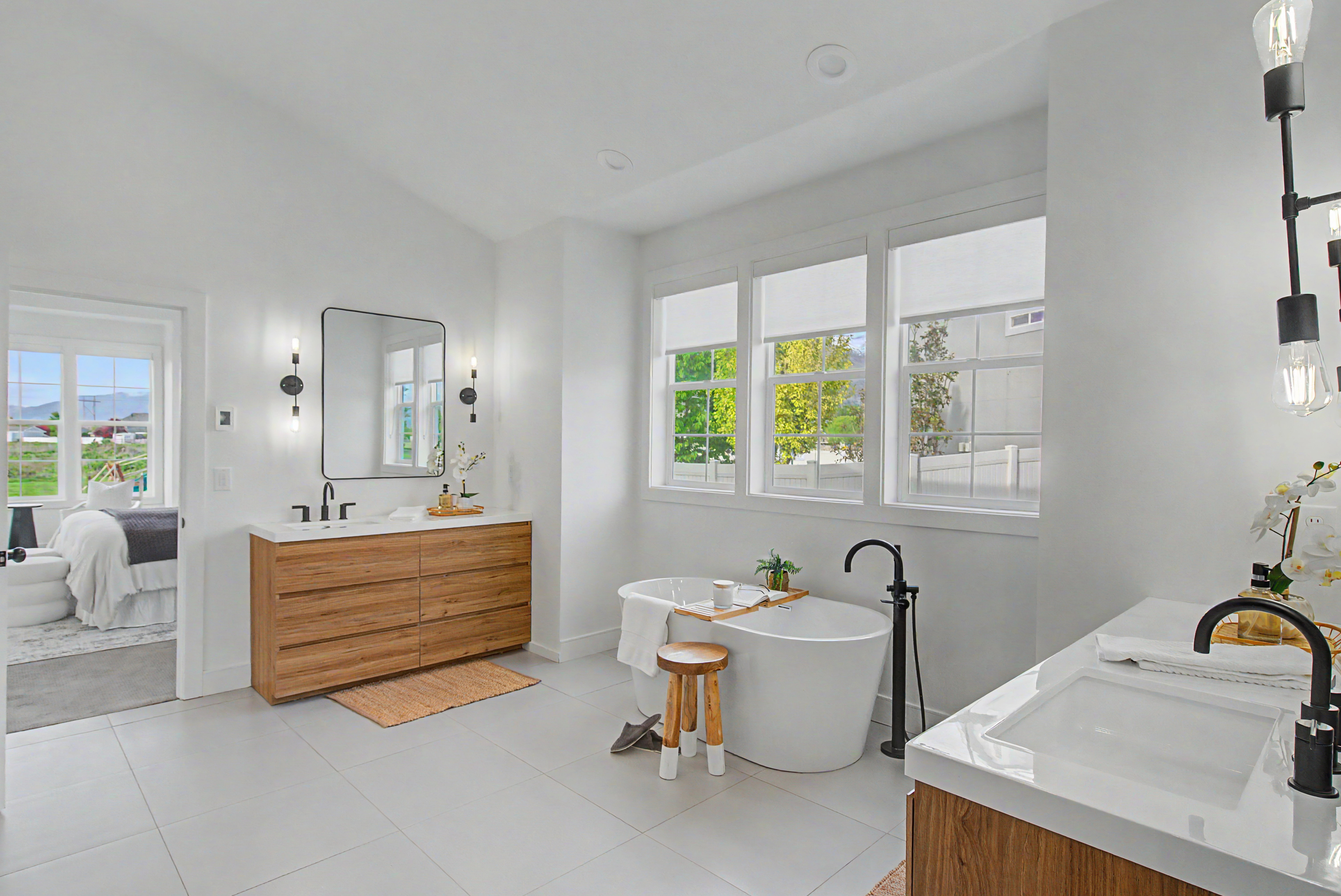 Ensuite bathroom featuring vanity, a freestanding bath, lofted ceiling, and light tile patterned floors