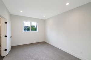 Empty room with light colored carpet and recessed lighting