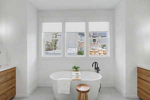 Full bathroom with vanity, a soaking tub, and light tile patterned floors