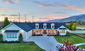 View of front facade featuring covered porch, roof with shingles, board and batten siding, driveway, and a mountain view