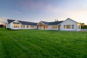 Modern farmhouse style home with board and batten siding, a yard, and a patio area