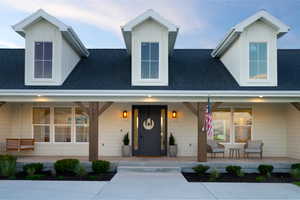 View of front of property with covered porch, a shingled roof, and board and batten siding