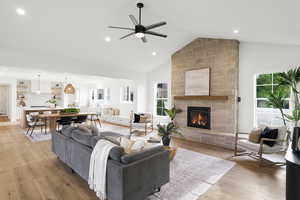 Living room featuring ceiling fan, a fireplace, light wood-type flooring, recessed lighting, and vaulted ceiling