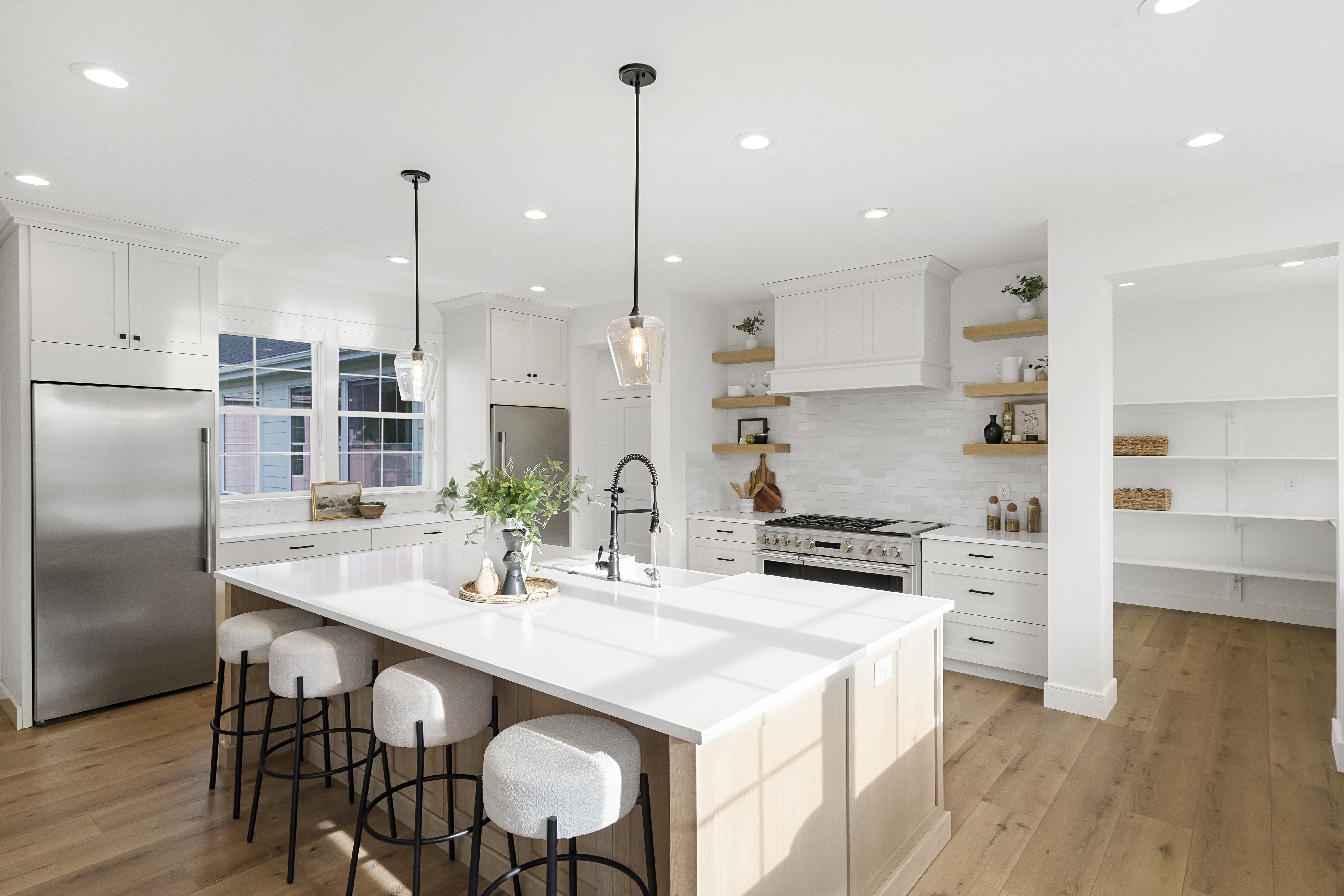 Kitchen featuring high quality appliances, light wood-style flooring, white cabinets, and a kitchen island with sink
