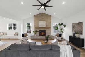 Living area with a ceiling fan, wood finished floors, a stone fireplace, and recessed lighting
