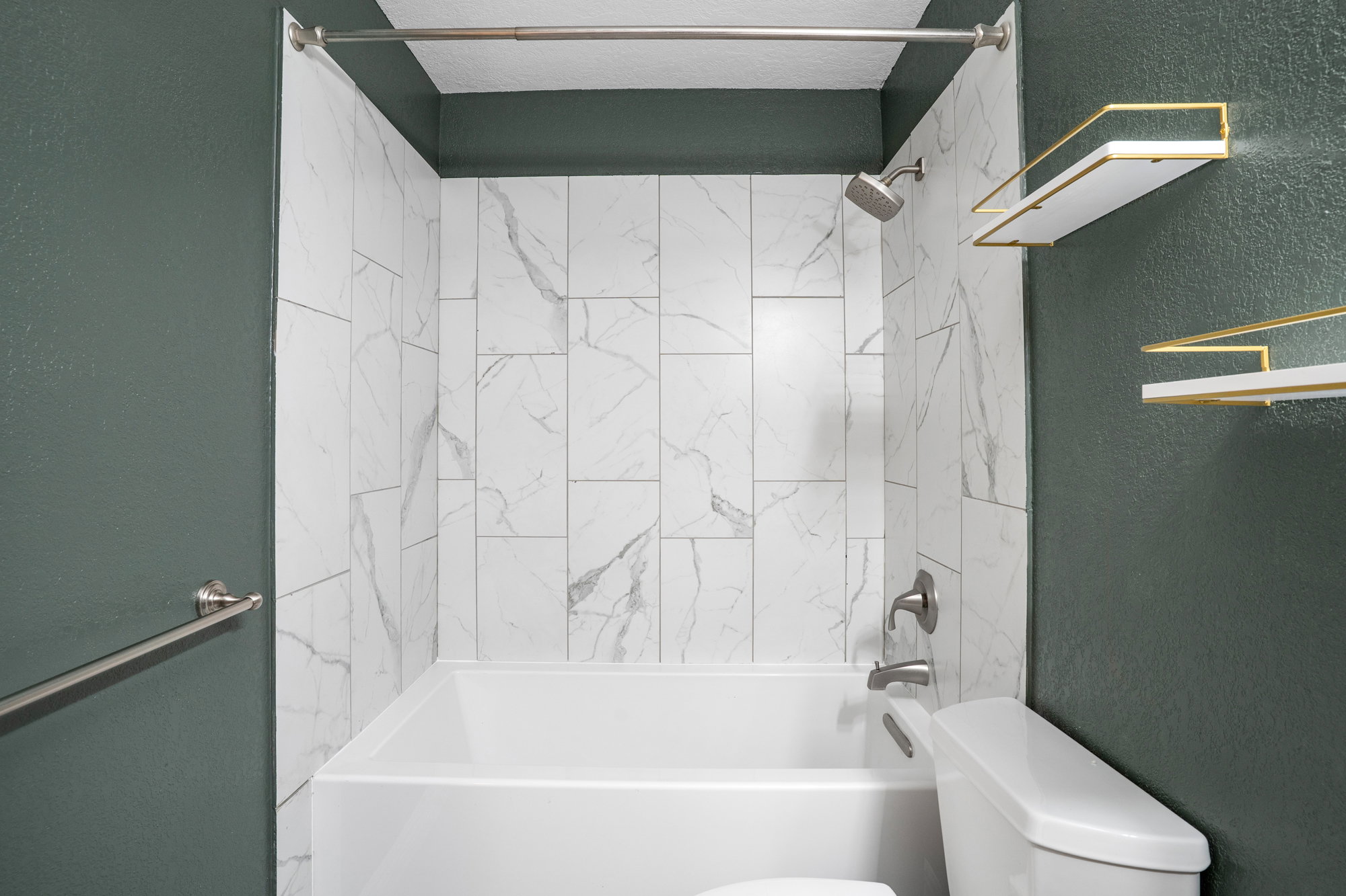Bathroom featuring a textured wall and shower / washtub combination