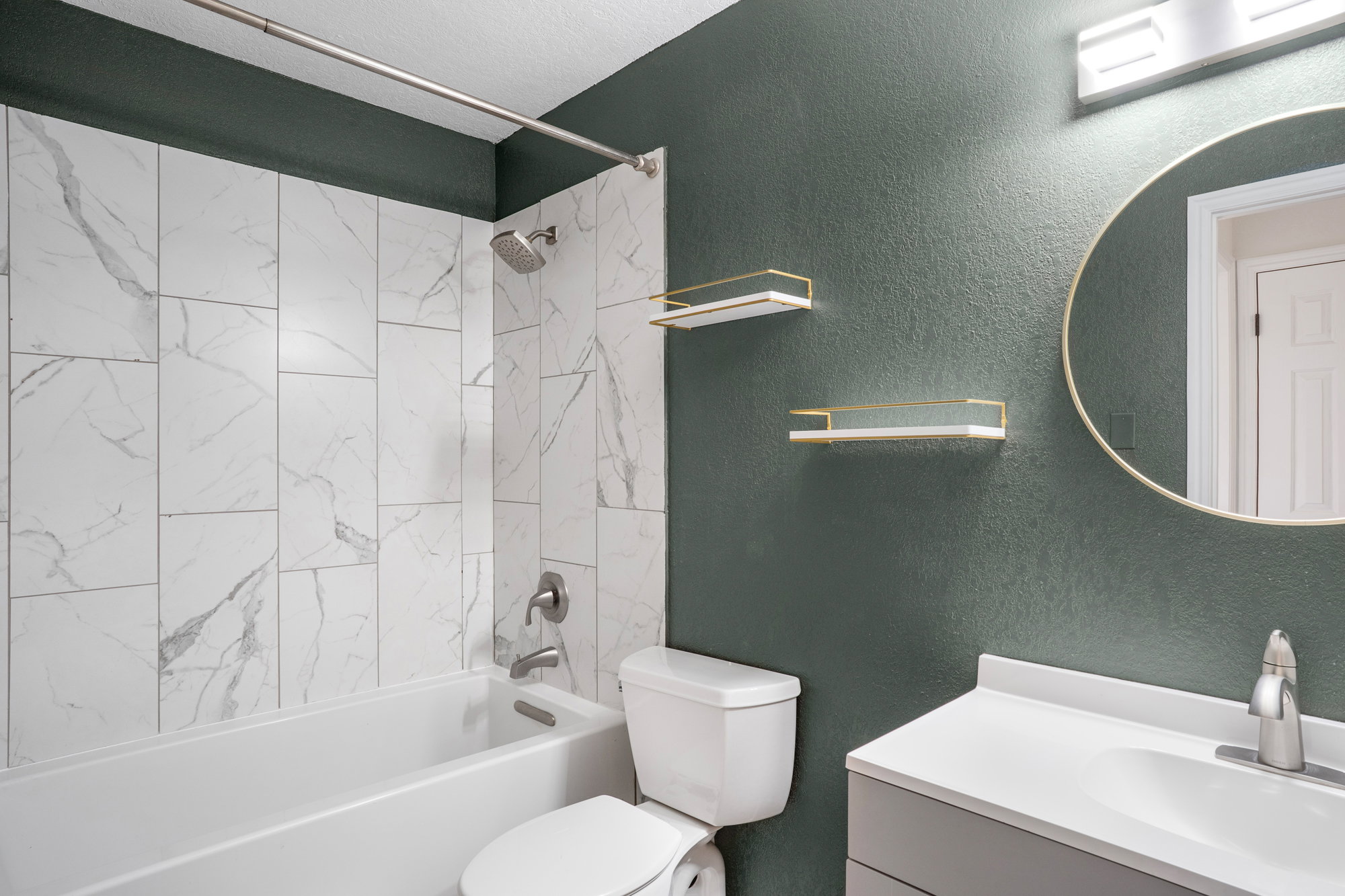Bathroom with a textured wall, vanity, and bathing tub / shower combination