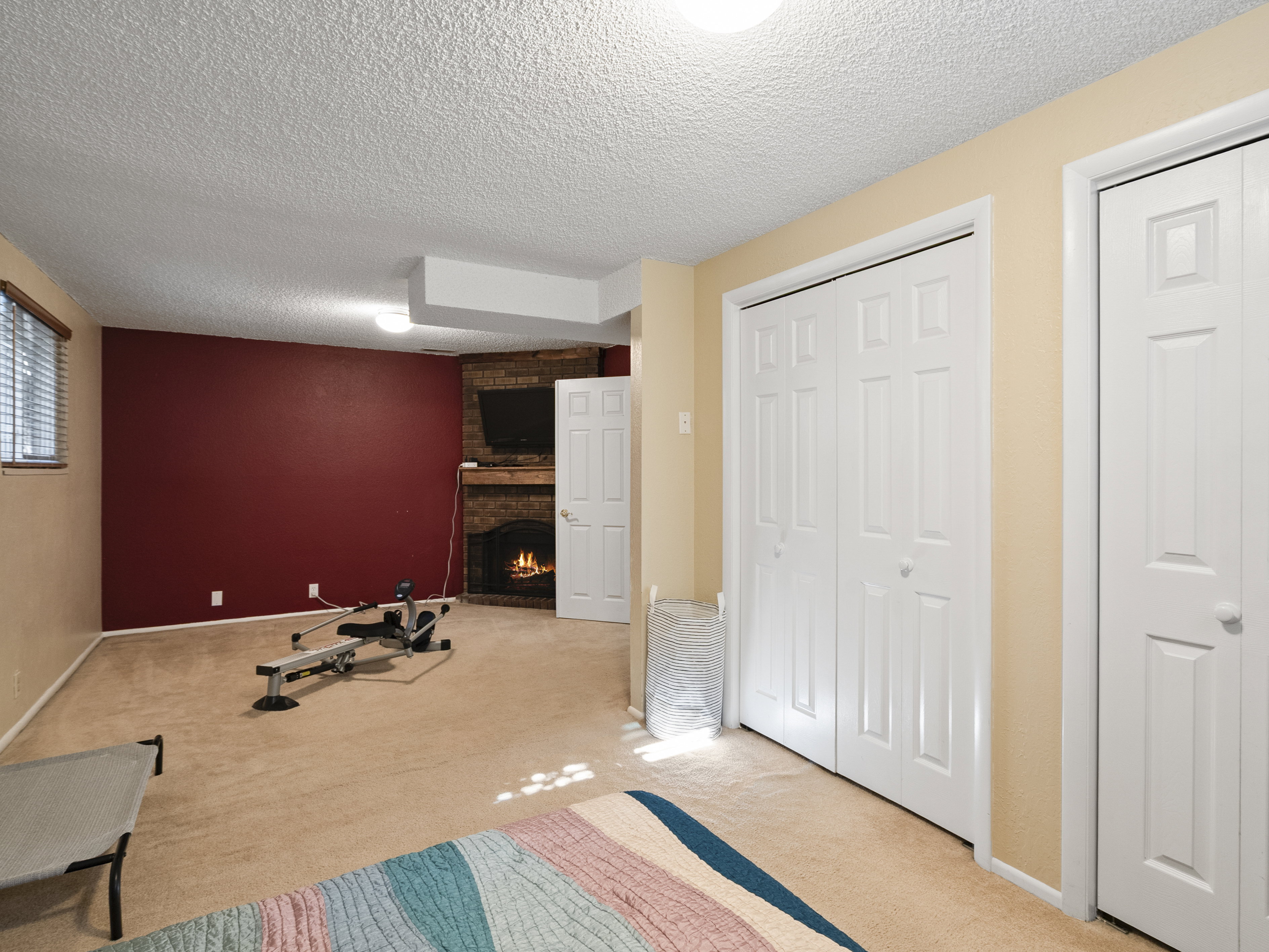 Unfurnished bedroom featuring multiple closets, a fireplace, light carpet, and a textured ceiling