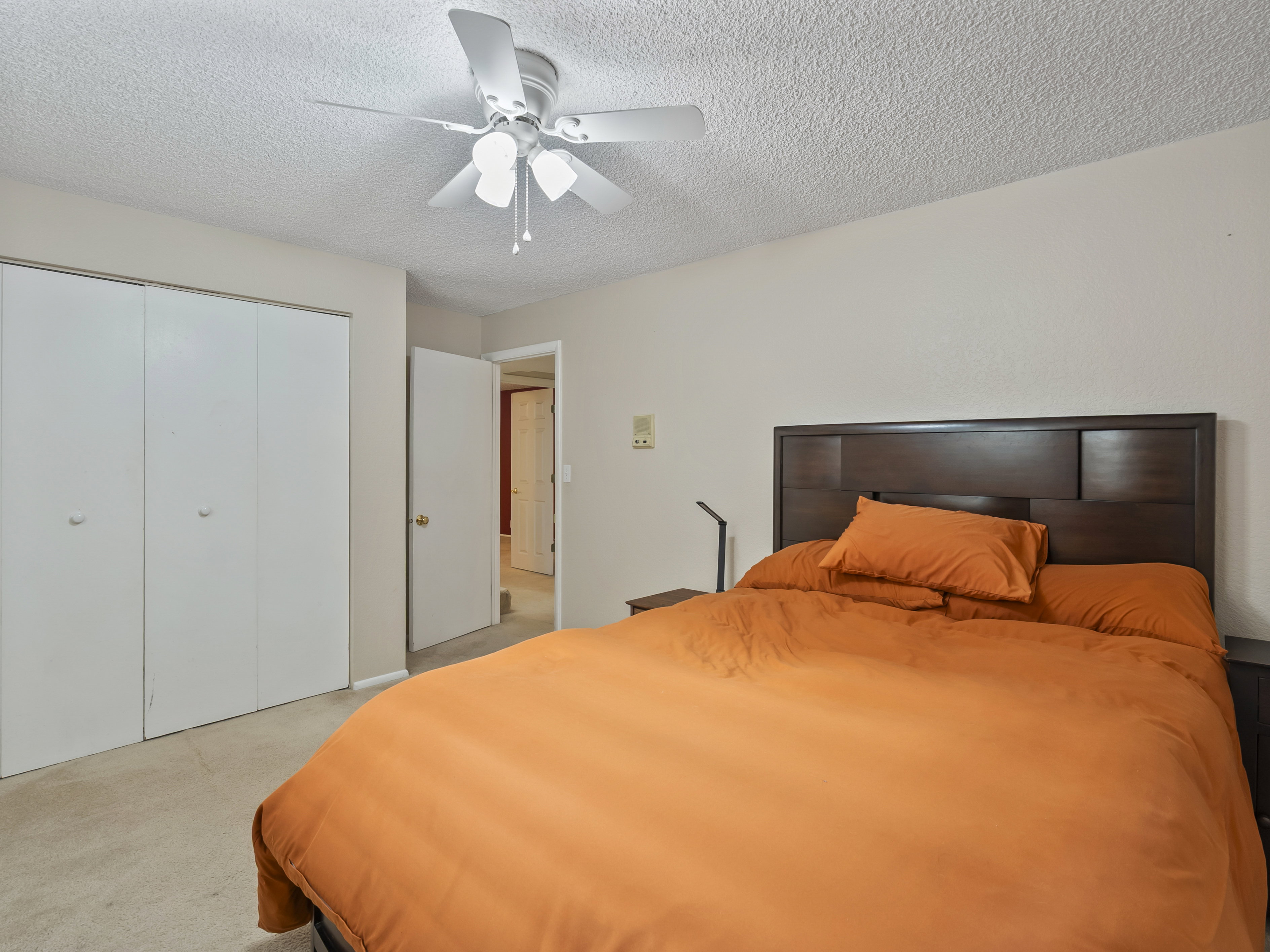 Bedroom featuring a textured ceiling, a closet, light carpet, and ceiling fan