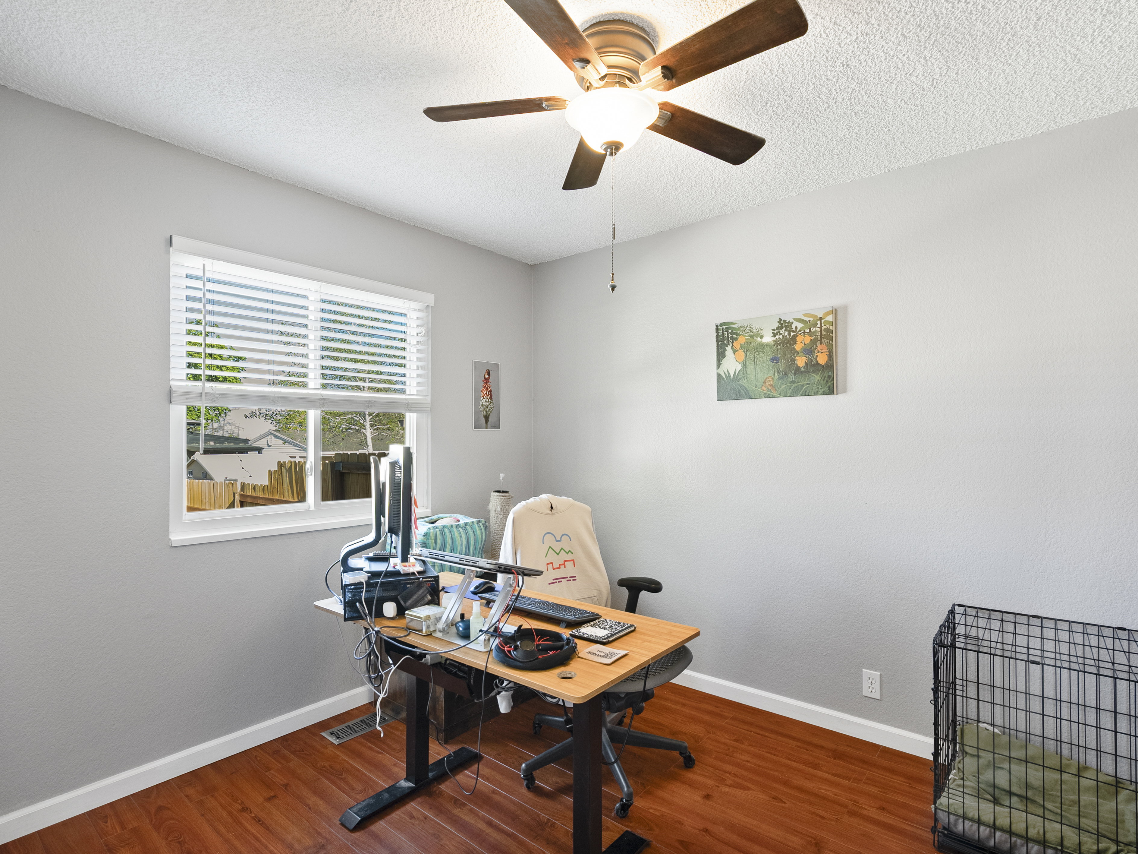 Home office with a ceiling fan, wood finished floors, and a textured ceiling