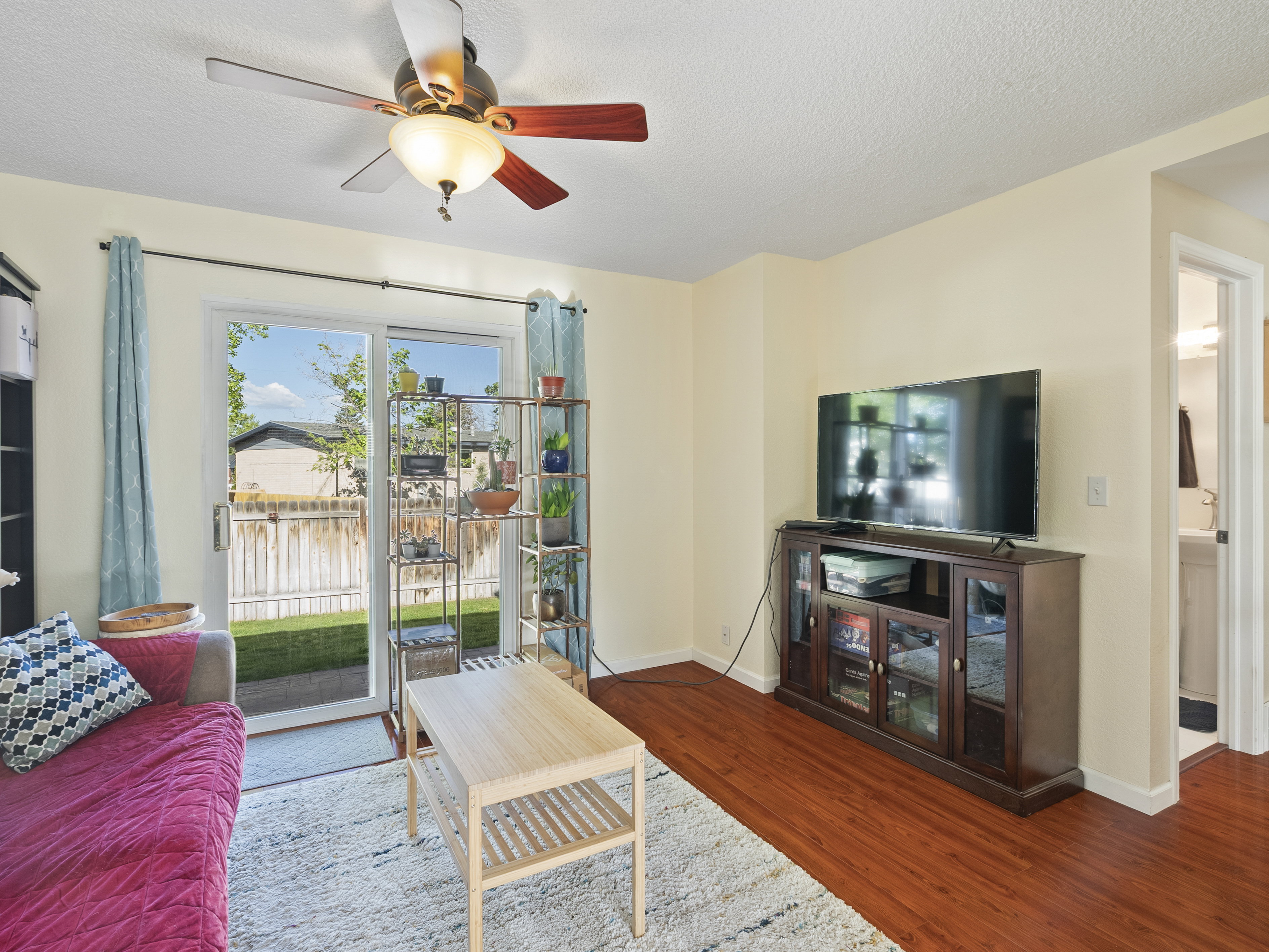 Living area featuring a ceiling fan, wood finished floors, and a textured ceiling