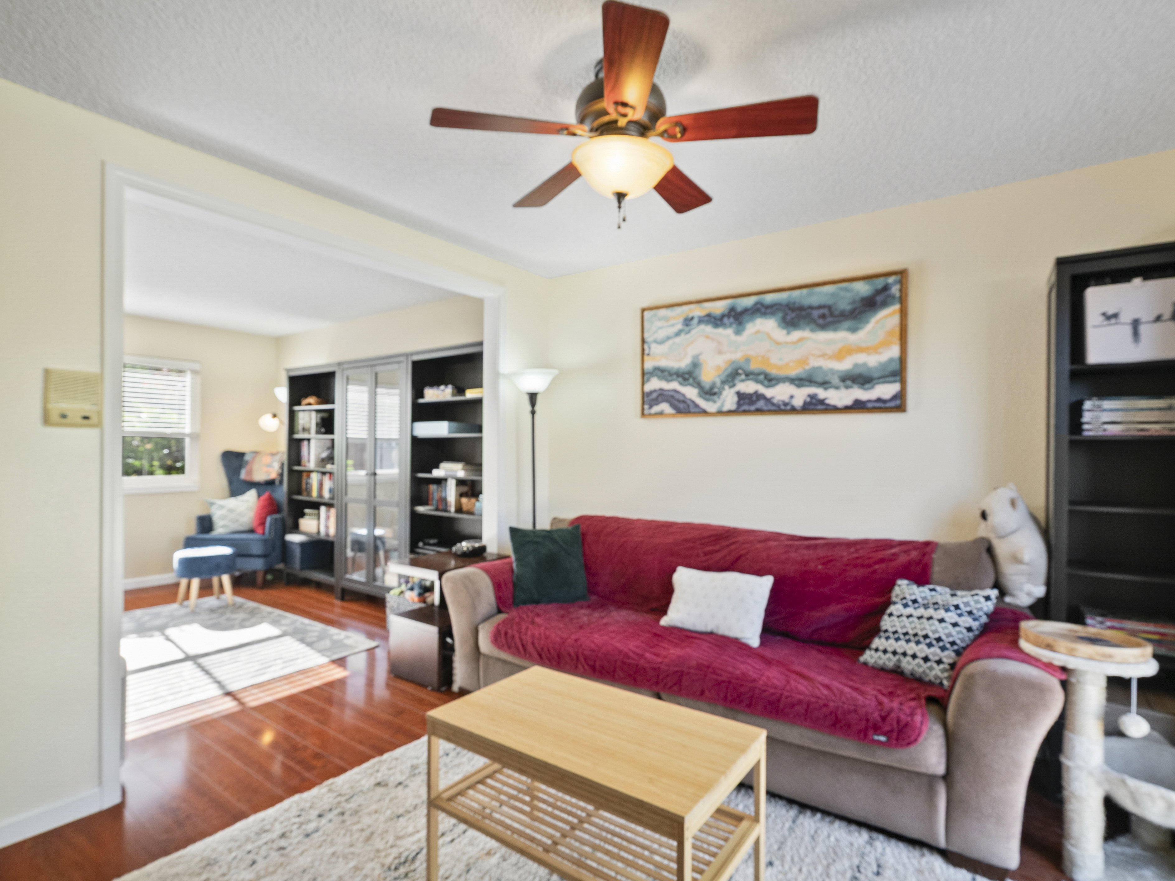 Living area featuring wood finished floors, a ceiling fan, and a textured ceiling