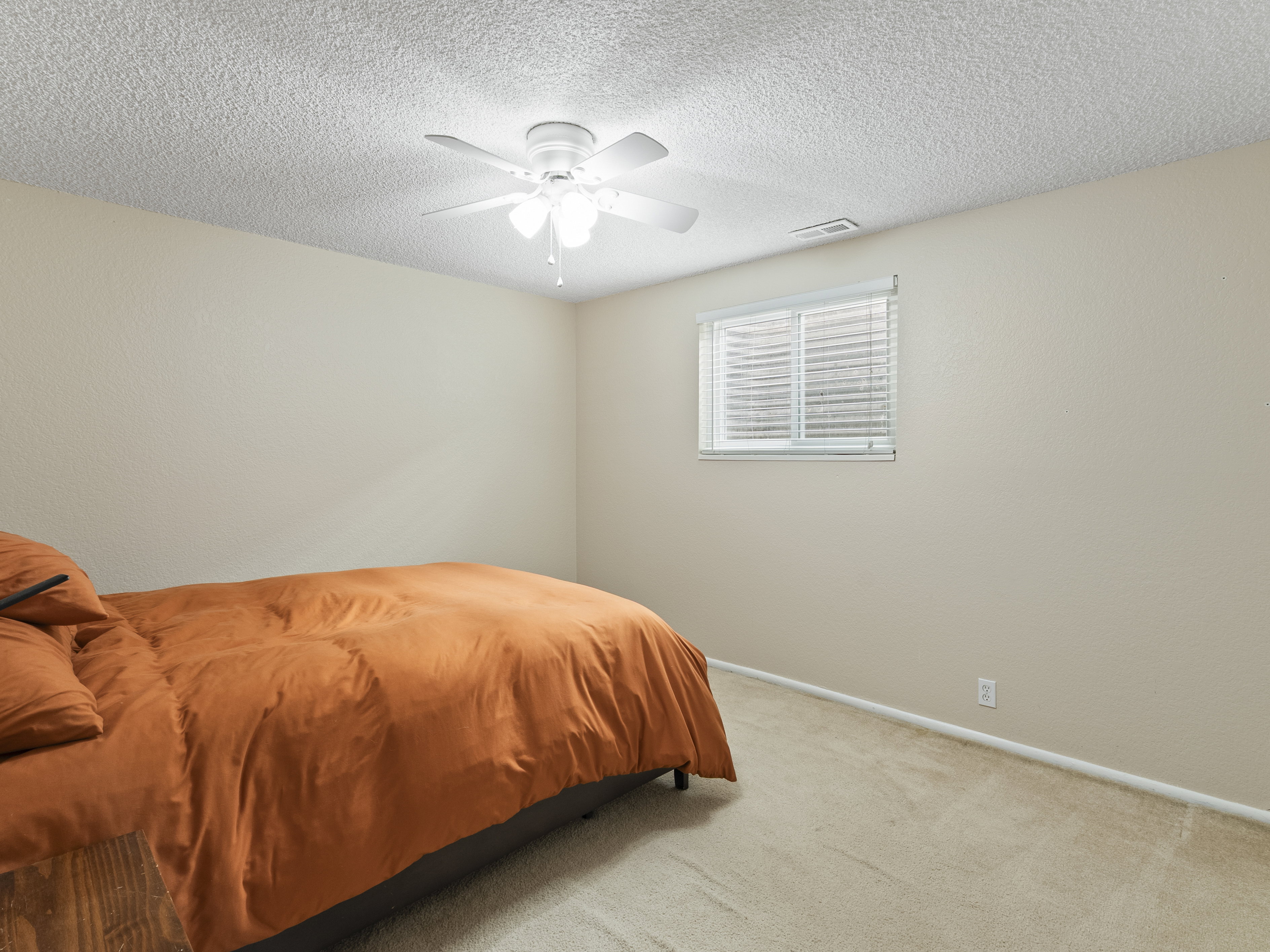 Bedroom featuring light colored carpet, a ceiling fan, and a textured ceiling