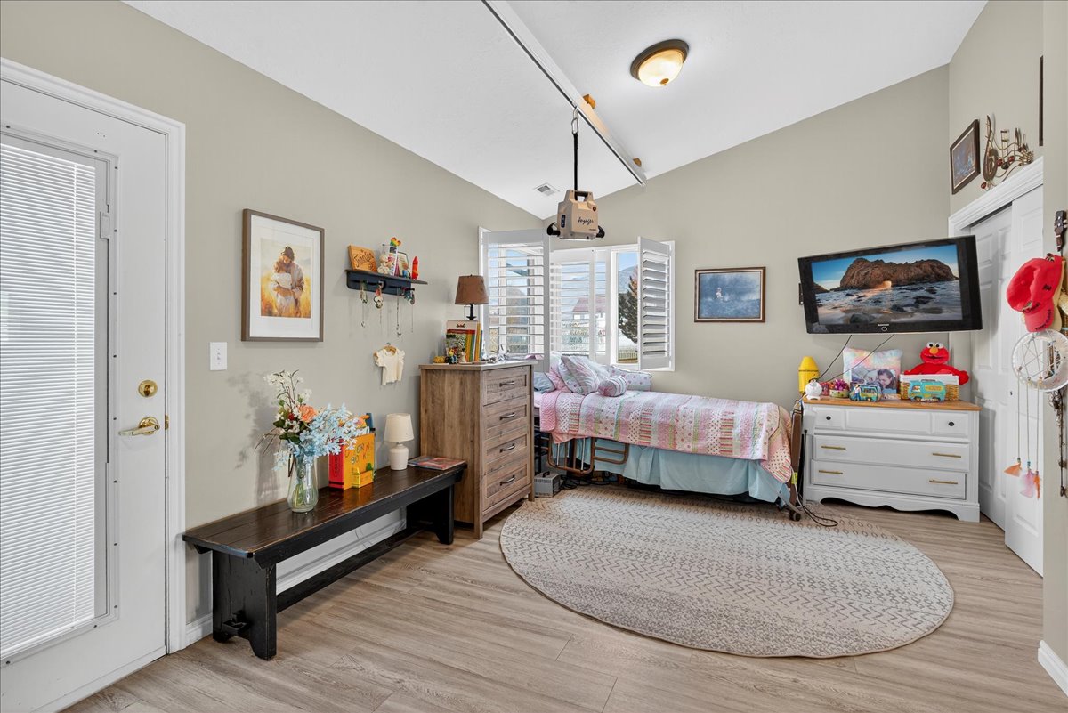 Bedroom with light wood finished floors and lofted ceiling