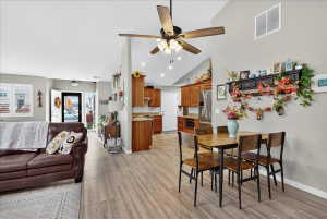 Dining room featuring light wood finished floors, vaulted ceiling, ceiling fan, and recessed lighting