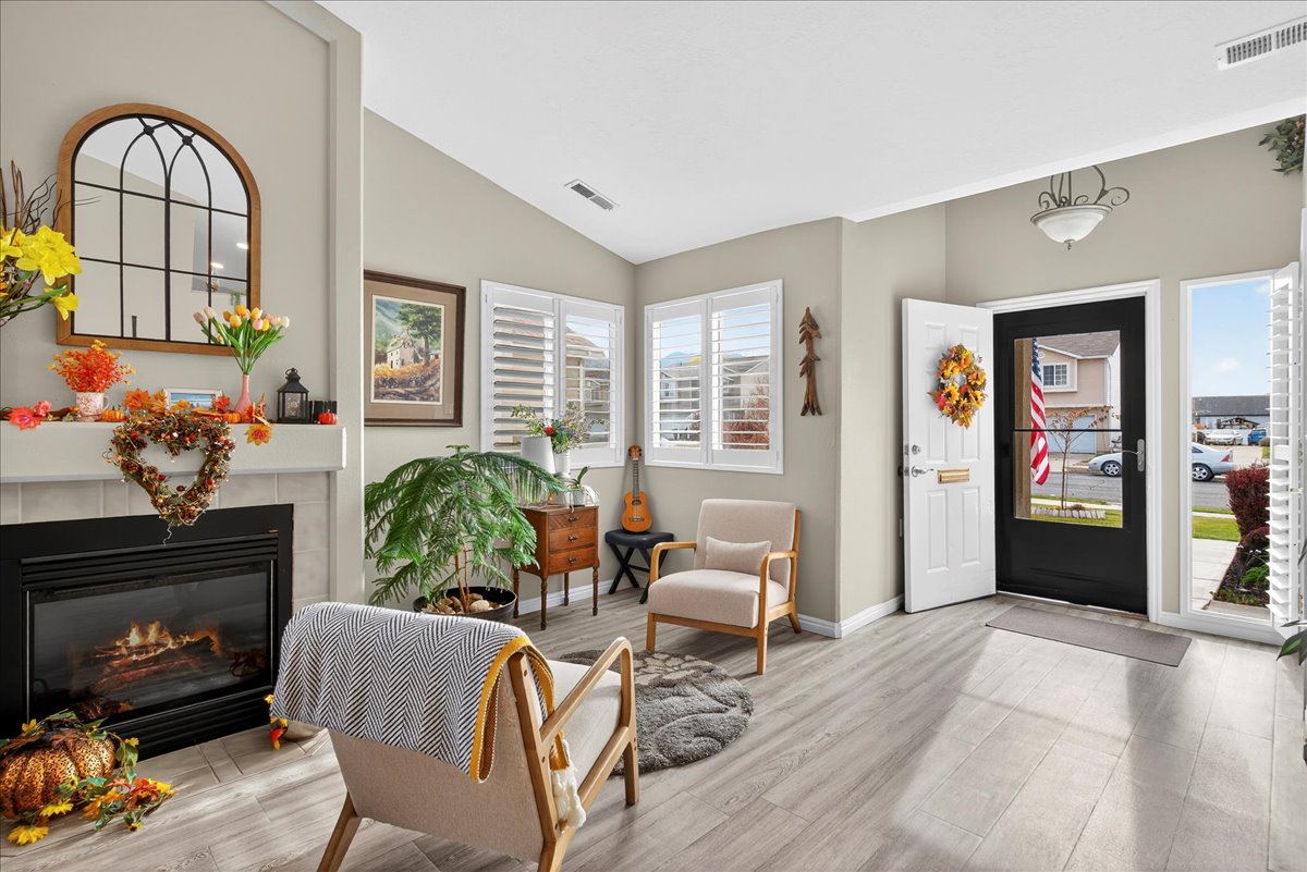 Foyer with a tiled fireplace, lofted ceiling, and light wood-type flooring