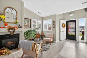 Foyer entrance with a fireplace, lofted ceiling, and light wood finished floors