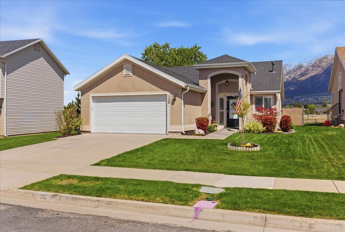 Single story home with stucco siding, a front lawn, an attached garage, and concrete driveway