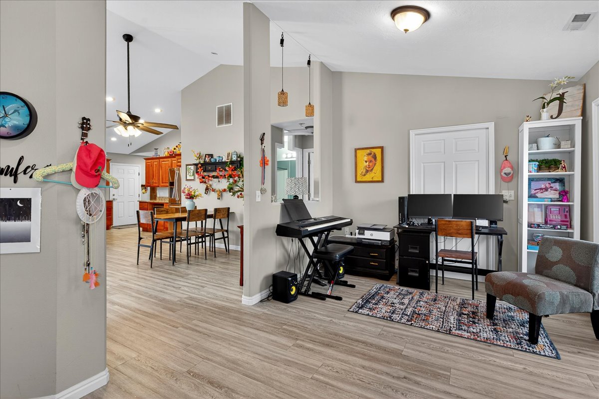Office with lofted ceiling, ceiling fan, and light wood finished floors