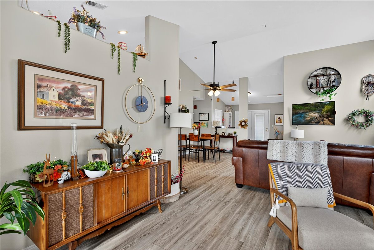 Living room featuring ceiling fan, light wood finished floors, and vaulted ceiling
