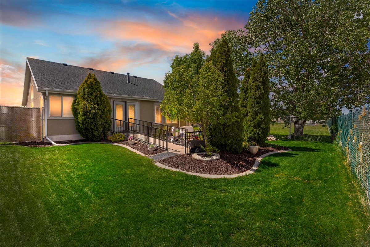 Back of house at dusk featuring a shingled roof and stucco siding