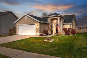 View of front facade featuring stucco siding, an attached garage, a front yard, and driveway