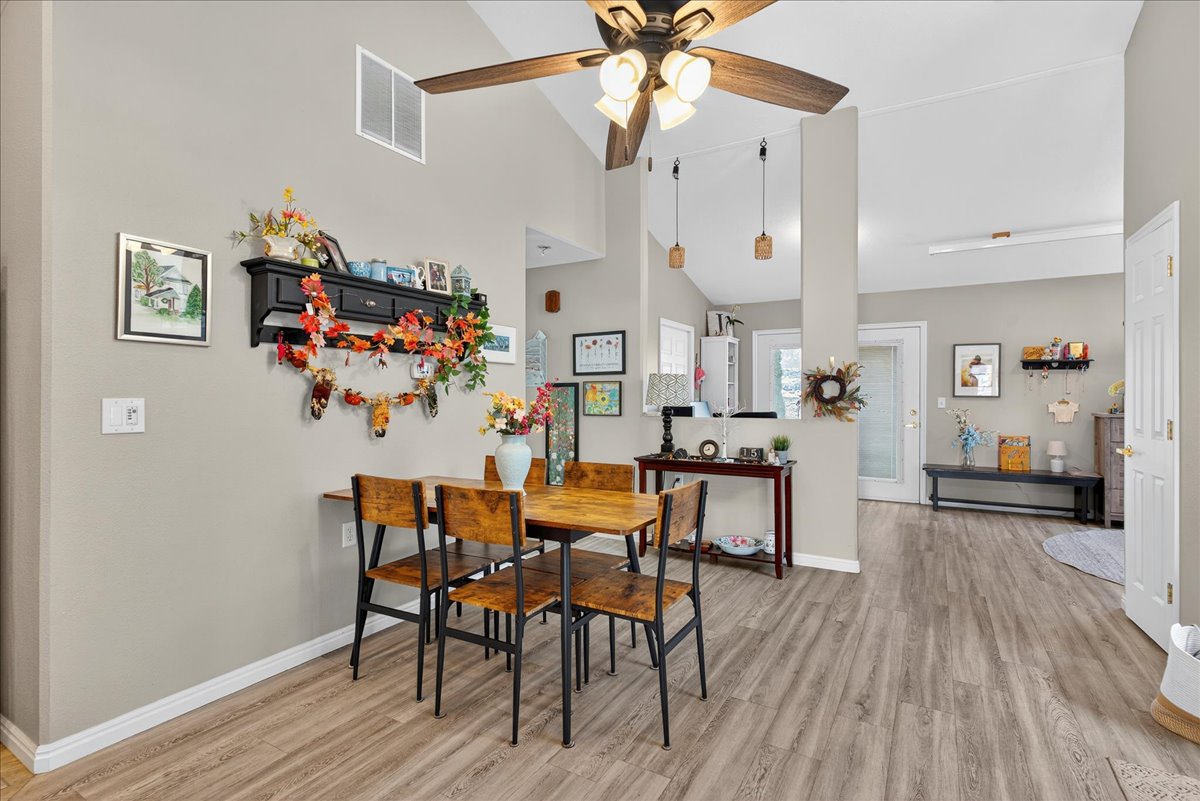 Dining area featuring vaulted ceiling, light wood finished floors, and ceiling fan