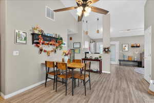 Dining area featuring vaulted ceiling, light wood finished floors, and ceiling fan