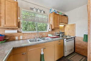 Kitchen featuring gas range gas stove, wooden walls, a textured ceiling, wallpapered walls, and light countertops