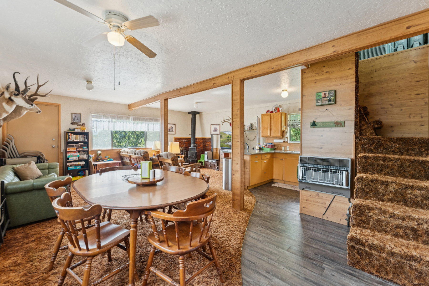 Dining room featuring a wood stove, dark wood finished floors, a ceiling fan, heating unit, and a textured ceiling