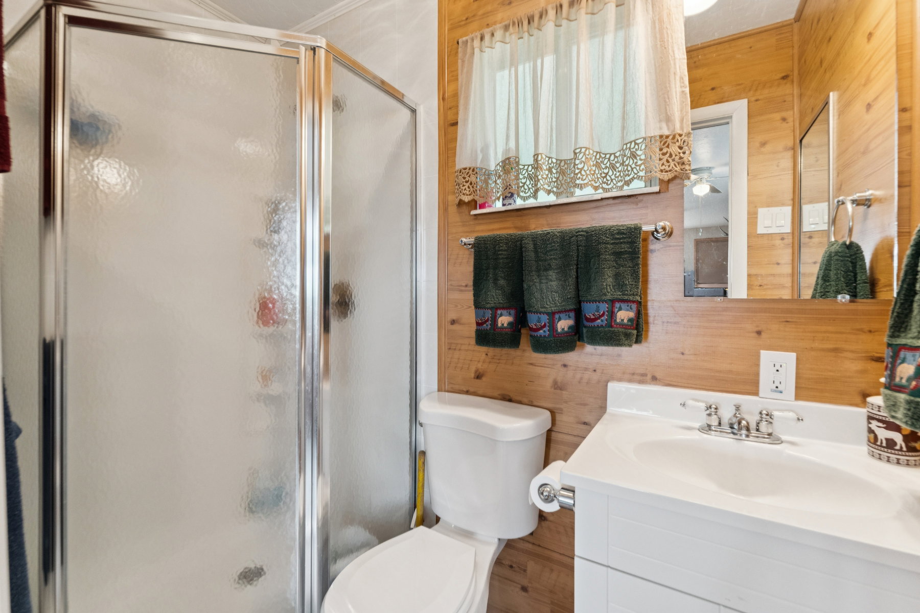 Bathroom featuring wooden walls, vanity, and a stall shower