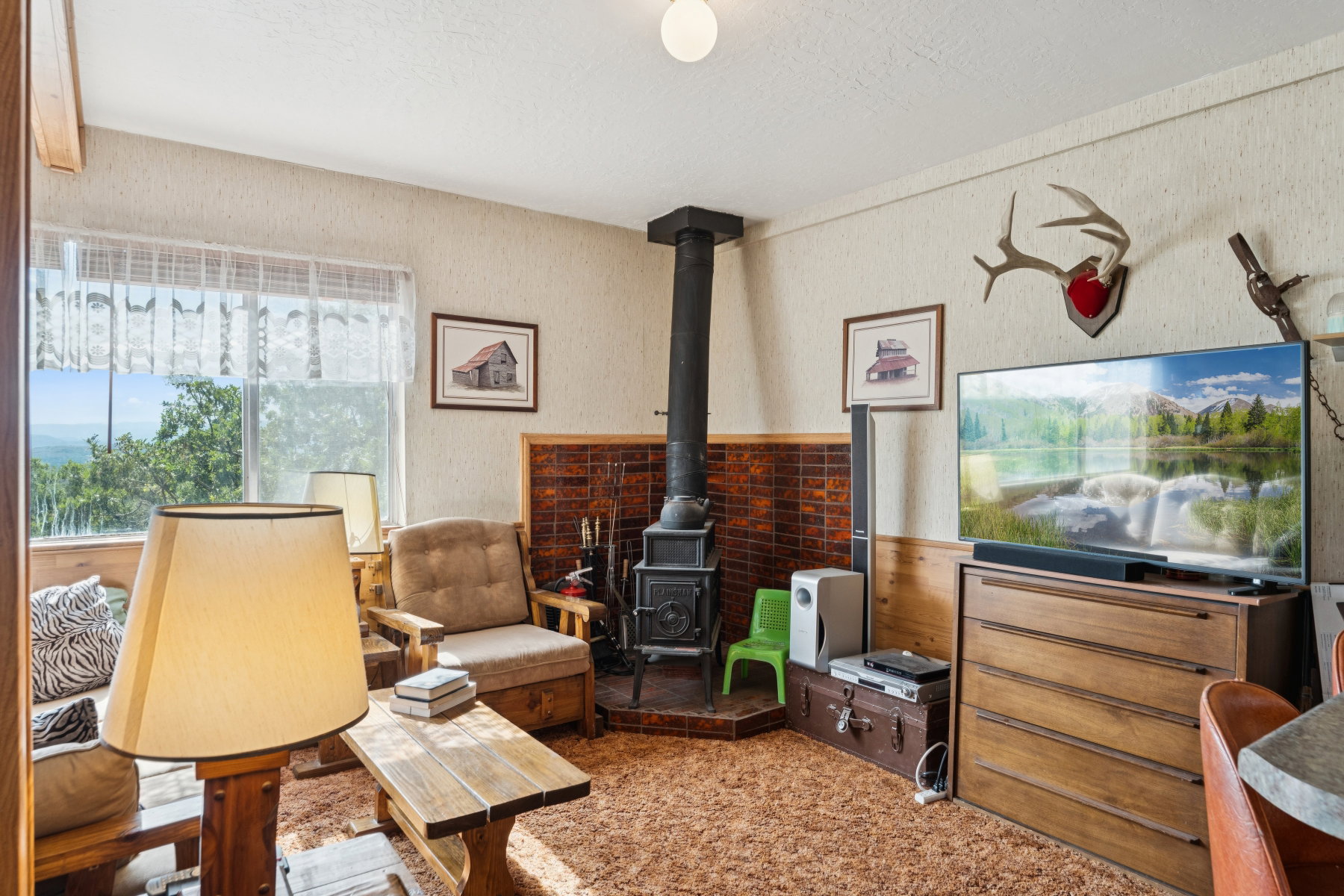 Living area featuring a wood stove, a textured ceiling, and wallpapered walls