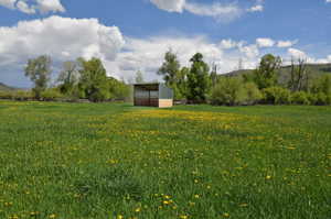 View of yard featuring a view of rural / pastoral area, an outdoor structure, a pole building, and a mountain view