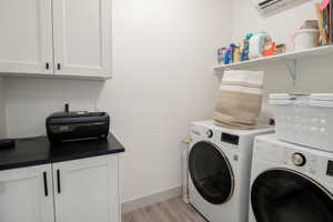 Laundry area featuring light wood-style floors, independent washer and dryer, and cabinet space
