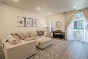 Living room with plenty of natural light, wood finished floors, and recessed lighting