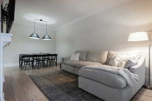 Living area with crown molding and light wood-style floors