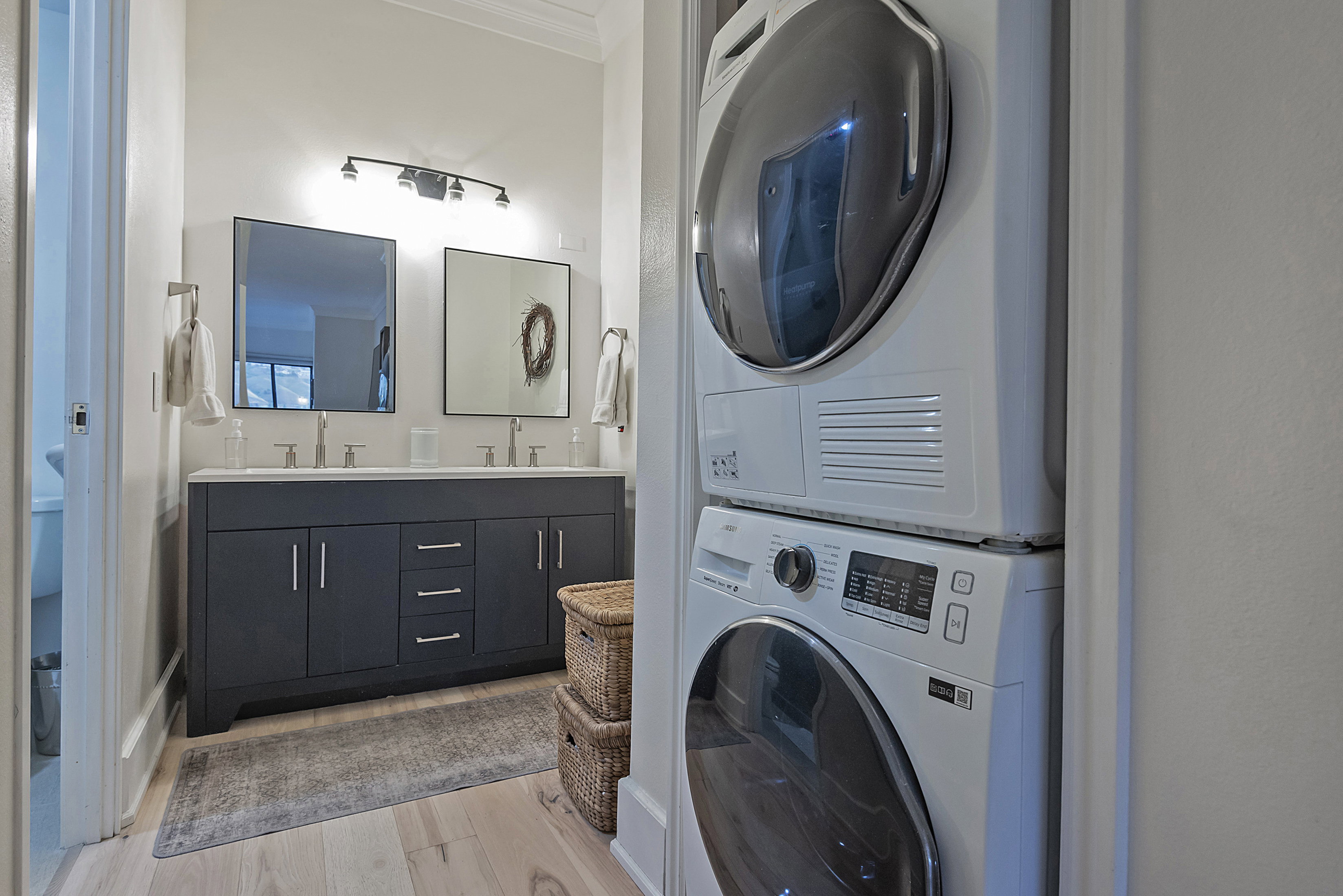 Laundry area featuring stacked washer / dryer, light wood finished floors, and crown molding