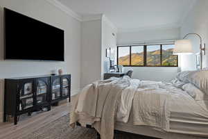 Bedroom featuring ornamental molding, wood finished floors, and a mountain view