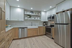 Kitchen with stainless steel appliances, open shelves, light wood finished floors, recessed lighting, and tasteful backsplash